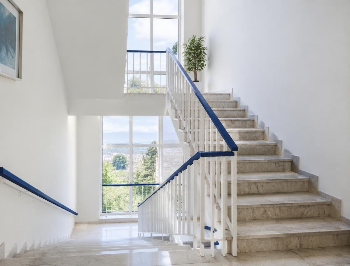Makelloses helles Treppenhaus mit polierten Stufen und blauem Handlauf
